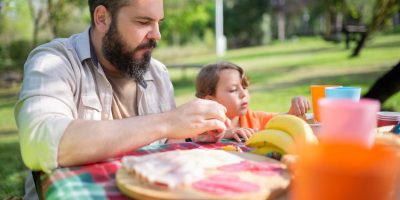Father and son bonding during a sunny outdoor picnic in a Portugal park.