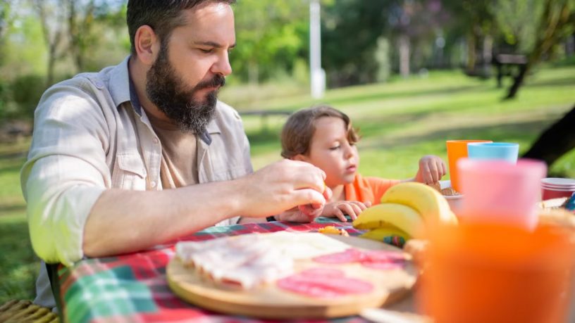 Father and son bonding during a sunny outdoor picnic in a Portugal park.